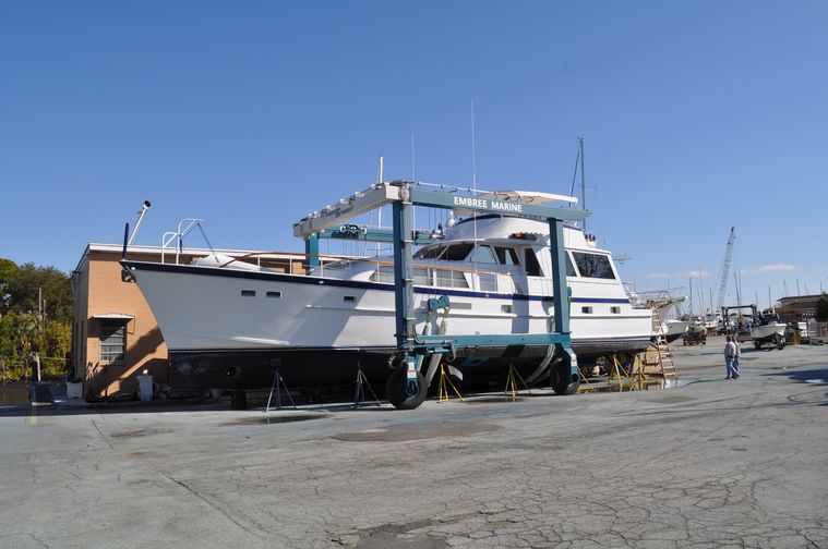 Motor yacht hoisted in a travel lift at Embree Marine boatyard.