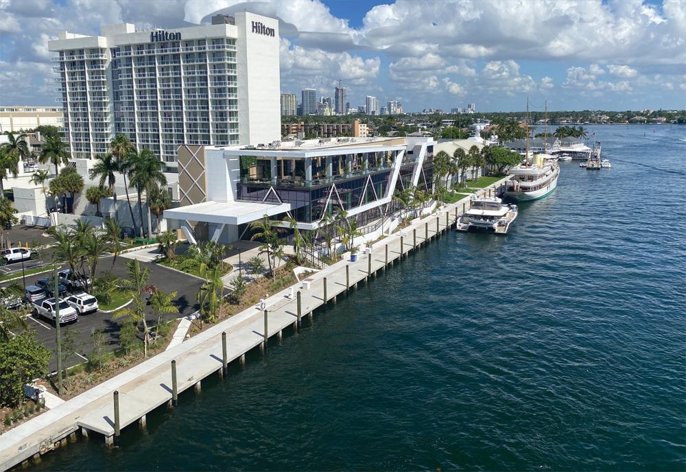 Waterfront Hilton hotel with a concrete dock promenade and moored yachts along the intracoastal waterway, Fort Lauderdale.