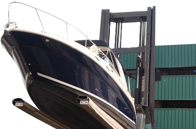 Dark blue sport cruiser being handled by a forklift near stacked green shipping containers, with wooden support blocks in the foreground.