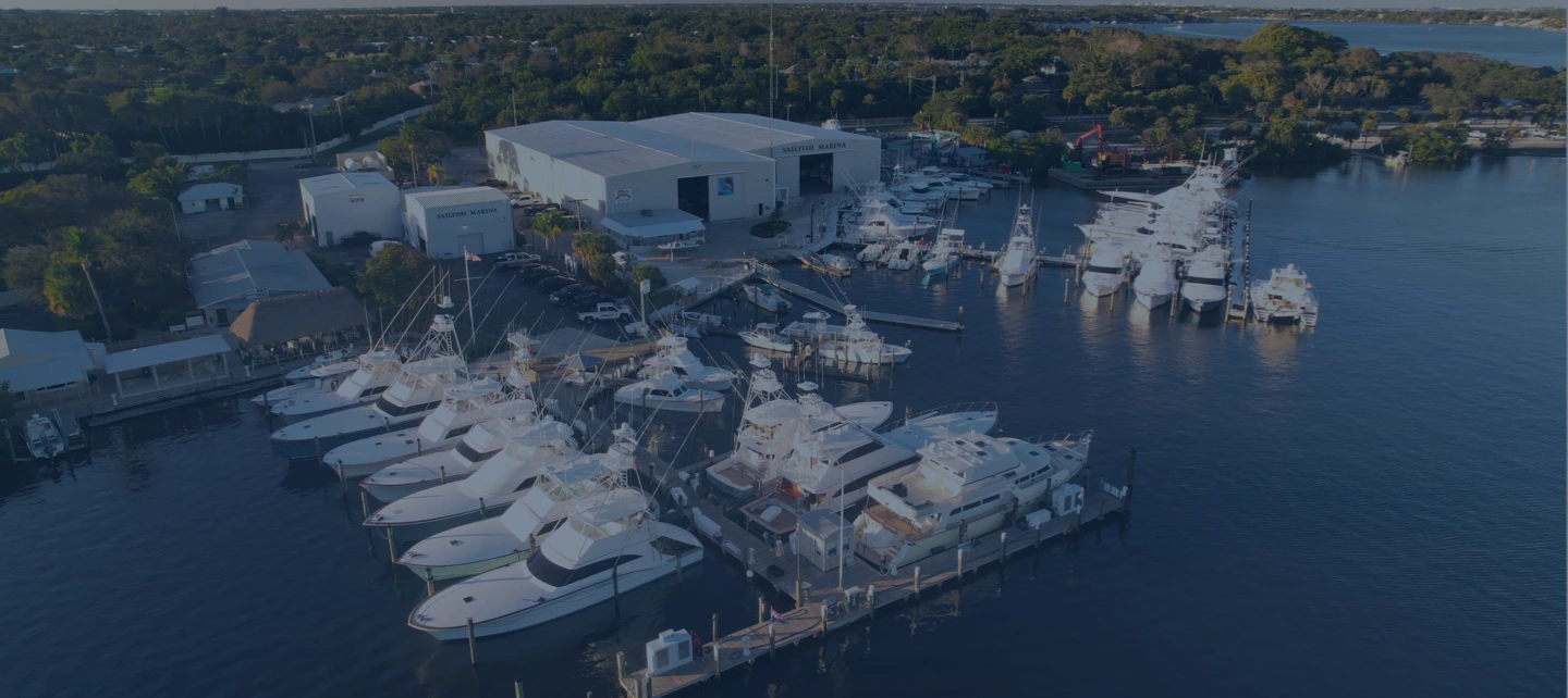 Aerial view of yachts docked along piers and a large boatyard building at Sailfish Marina, Stuart.