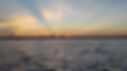 Sunset rays over open water on the horizon, with no identifiable business shown.
