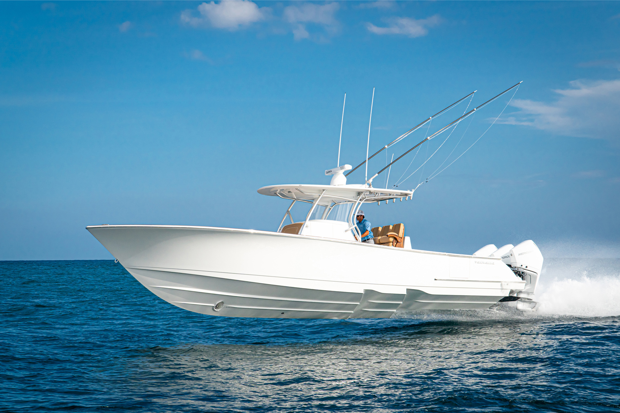 White center console sport fishing boat with Mercury outboards and a Garmin radar underway on open blue water.