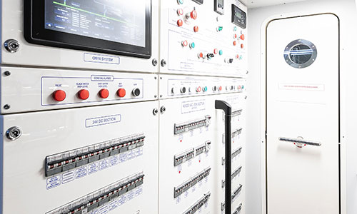 Marine electrical switchboard with breakers, alarm and control indicators, and a 24V DC distribution section inside a vessel's equipment space.
