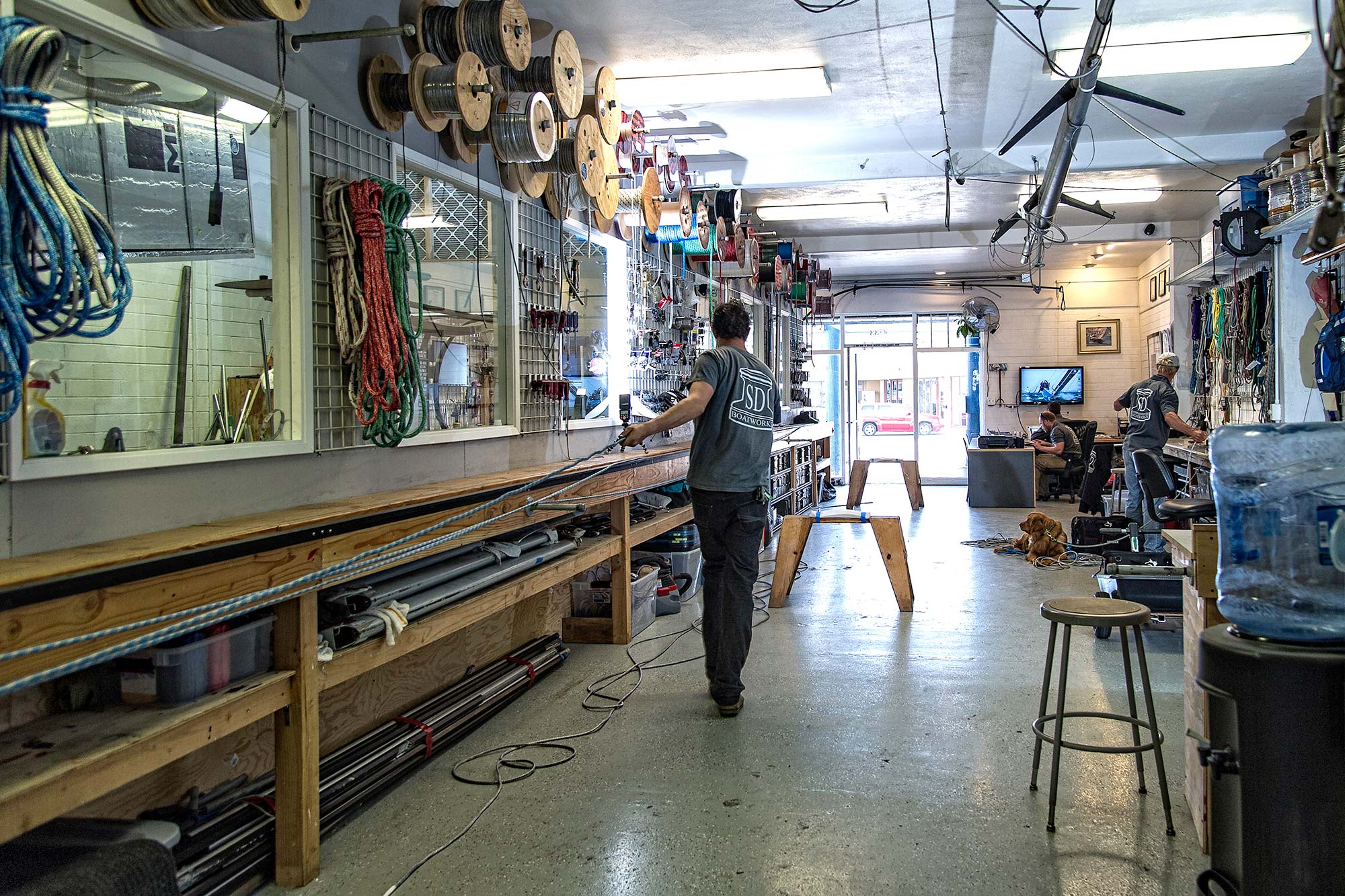 Interior workshop at SD Boatworks with rope and wire spools on the walls and staff working on rigging equipment, San Diego.