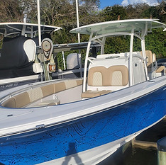 Center console fishing boat with a blue hull and tan upholstered seating at a marina dock.