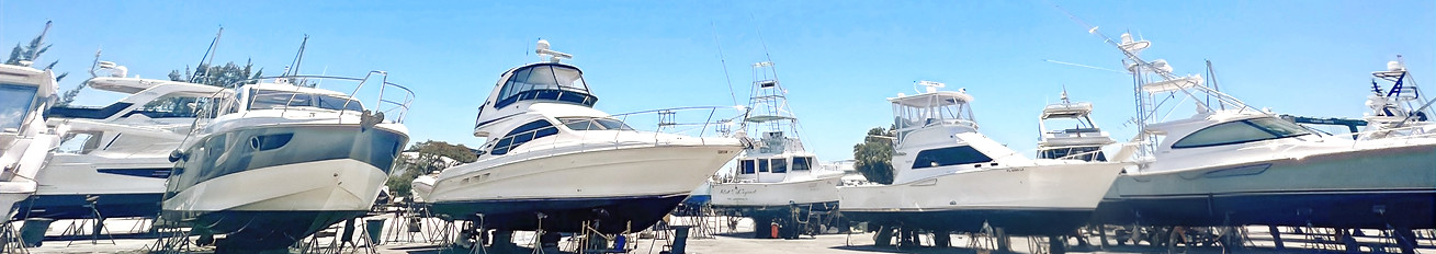 Yachts and sportfishing boats raised on stands in a boatyard, with no business name or town visible.