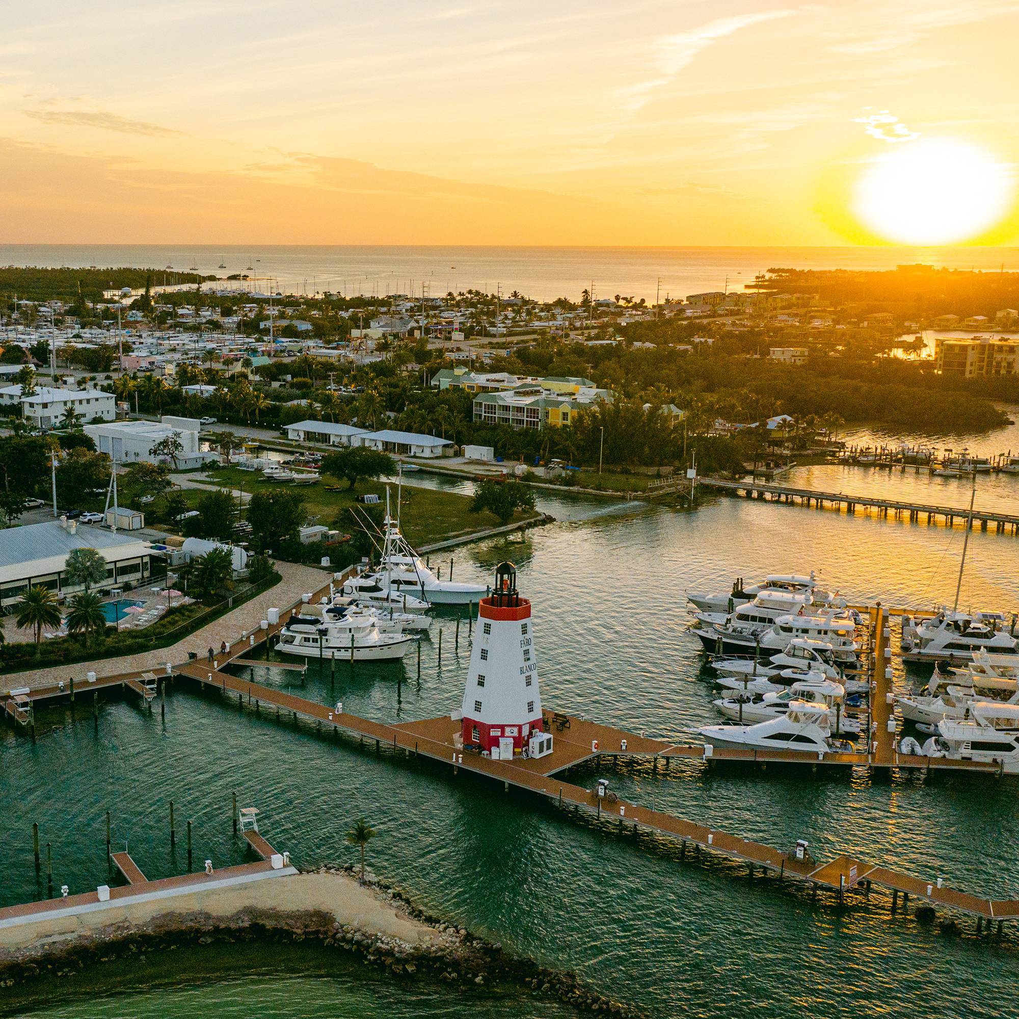 Aerial sunset view of the Faro Blanco lighthouse and docked yachts at Faro Blanco Marina, Marathon.