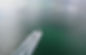 Blurred view of a white boat hull above green water, with business and town unknown.