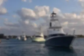 Sportfishing motor yacht and smaller boats on open water at dusk, with no specific business identified.