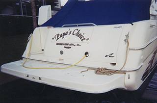 Stern of the white motor yacht Papa's Choice with a blue canvas cover and a coiled dock line on the swim platform.