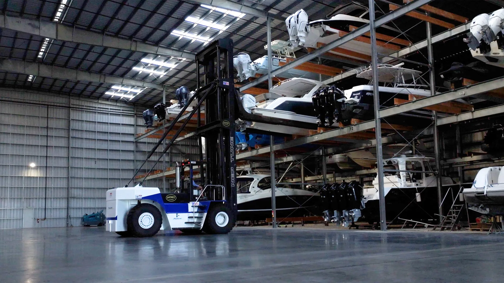 Hoist Liftruck boat-handling forklift lifting a powerboat in an indoor multi-level boat storage facility.