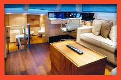 Yacht cabin interior with wood flooring, a white sofa, and a wooden coffee table.