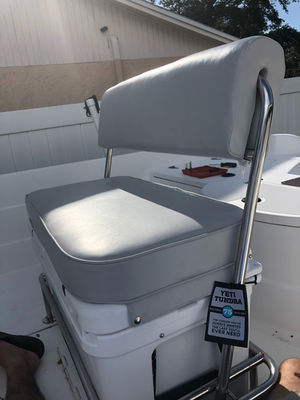 Grey upholstered boat helm seat on a stainless steel frame, installed on a boat deck.