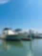 White motor yacht moored at a marina dock on a sunny day.