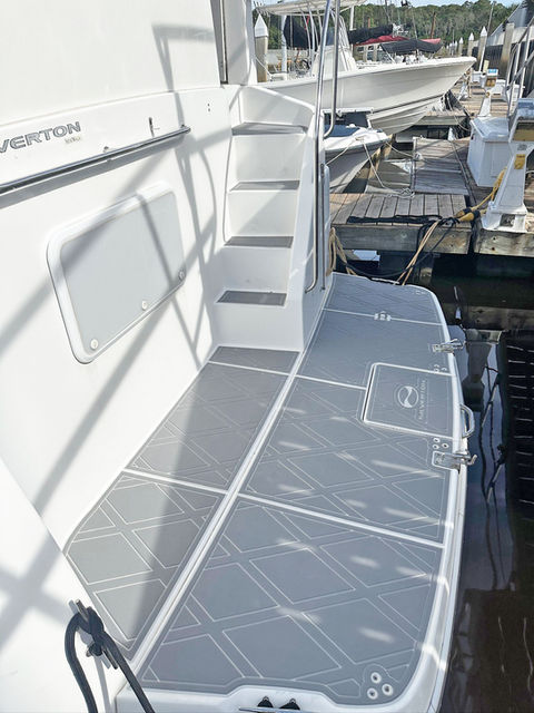 Stern boarding area with grey diamond-pattern synthetic non-slip decking and steps on a Viking-style Verton yacht at a marina dock.