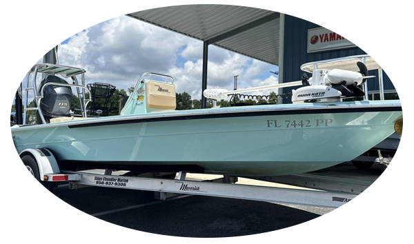 Light blue flats boat on a Triton trailer at Shoo Chandler Marine, Destin, with a Yamaha sign in the background.