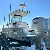 White center-console boat with twin Yamaha outboard motors docked at a marina.