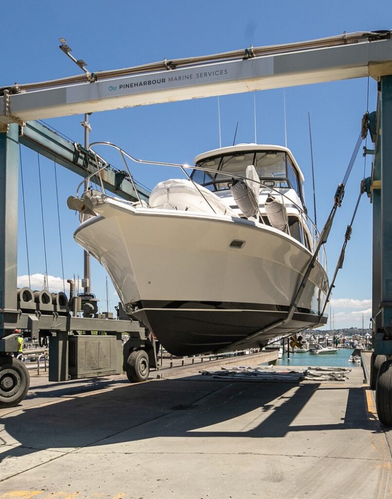 White motor yacht being lifted by a travel hoist at Pineharbour Marine Services, Auckland.