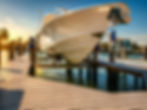 White motorboat raised on a lift over a dock at sunset.