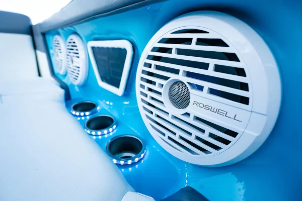 White Roswell marine speakers and illuminated cup holders in the blue-lit interior of a boat.