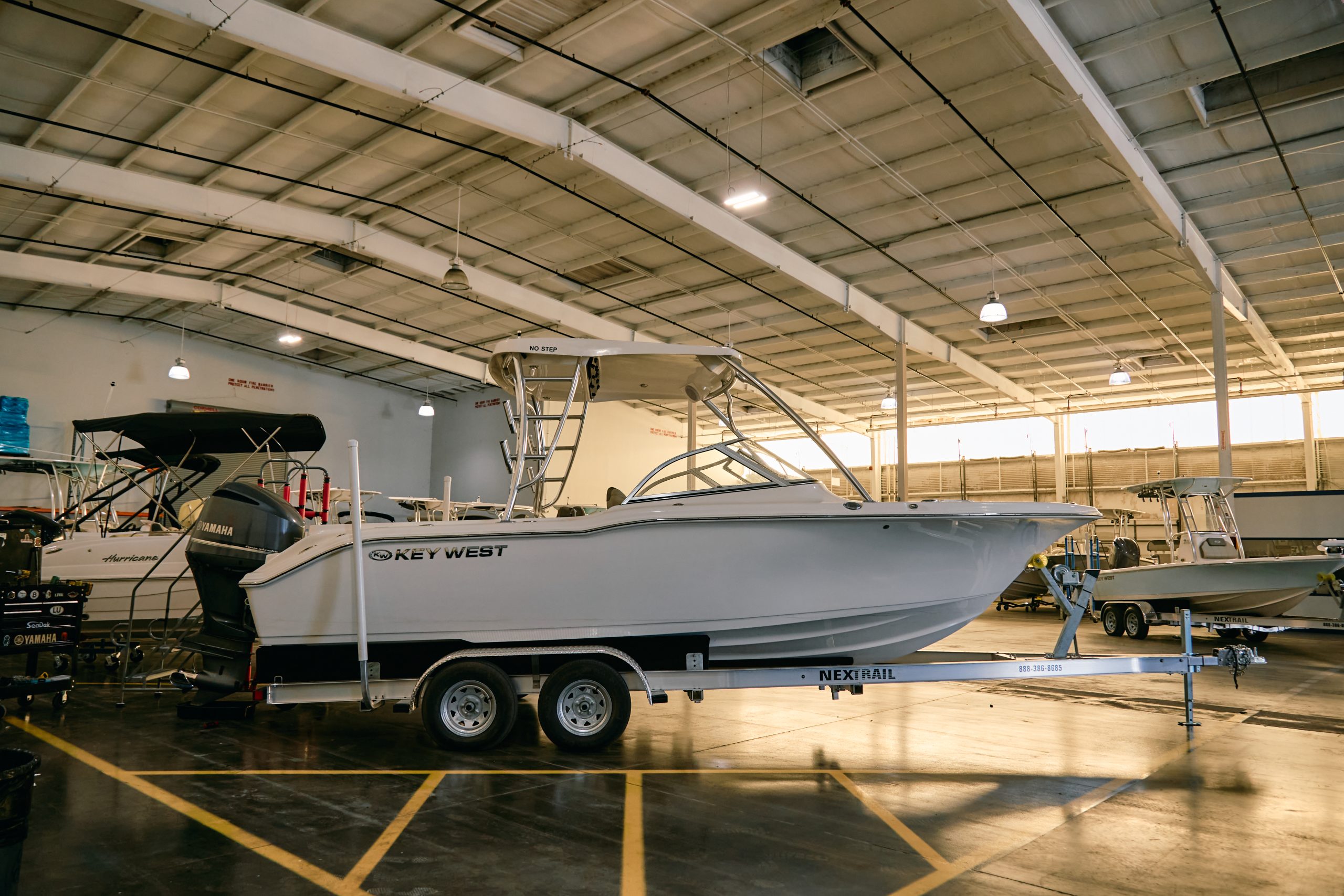 Key West walkaround boat on a NEXTRAIL trailer, displayed indoors among other boats in a dealership showroom.