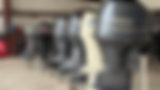 Row of outboard motors lined up on stands in a service shop.