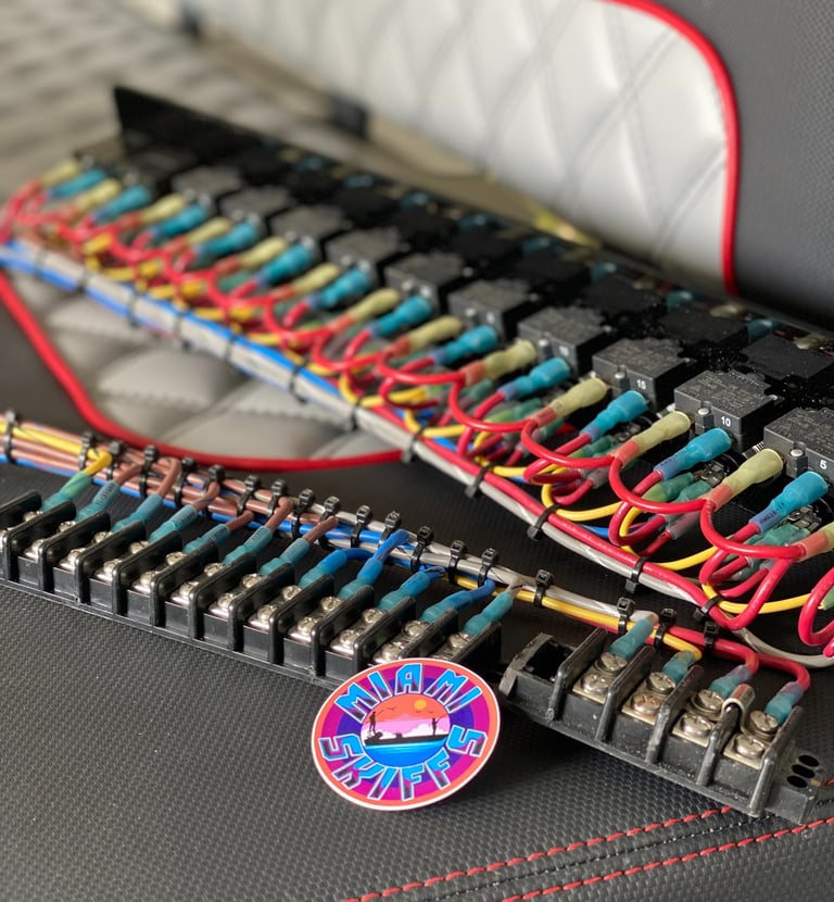 Marine electrical wiring panel with relays, fuses and terminal blocks on a boat seat at Miami Skiffs, Miami.