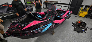 Pink and black wrapped jet ski in a workshop at JP Racing, town unknown.