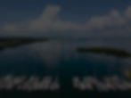 A calm bay with dark water and wooded shorelines under a cloudy sky.