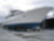 Large white sport fishing boat with blue accents sitting on stands in a boatyard.