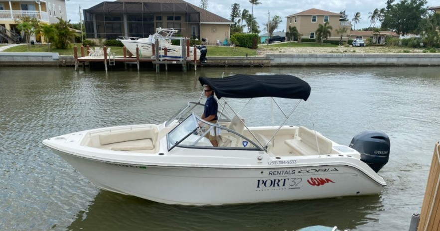 Cobia center-console rental boat with black bimini top on a canal at PORT 32 Marine Rentals, Marco Island.