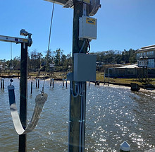 Electrical enclosures and wiring mounted on a dock piling at a waterfront marina.