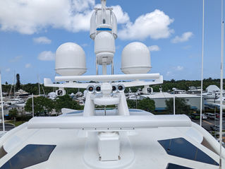 Radar domes, antenna mast and navigation equipment on the flybridge of a motor yacht at a marina.