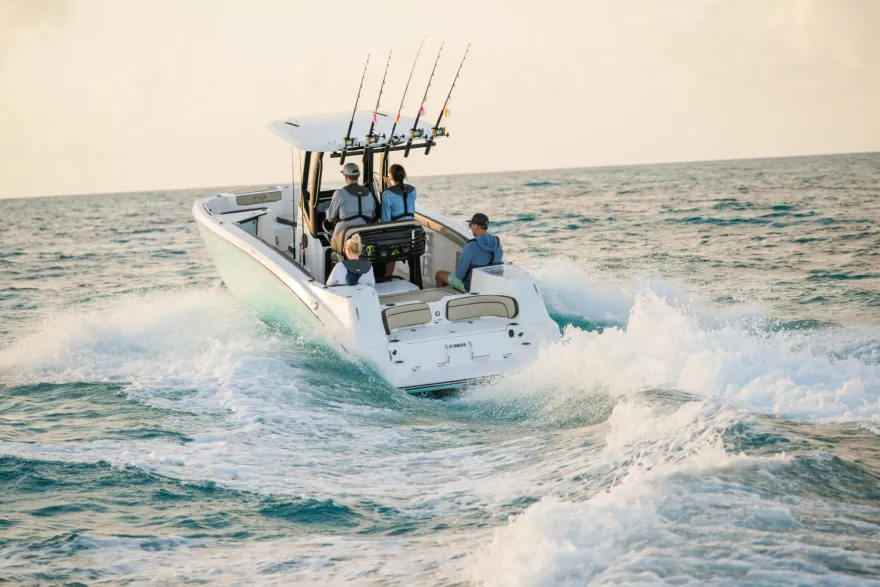 Center-console fishing boat with rod holders and three passengers running at speed across open water.