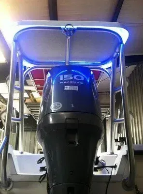 Outboard motor with a 150 four-stroke badge mounted on a boat's T-top frame, lit by blue underglow LEDs.