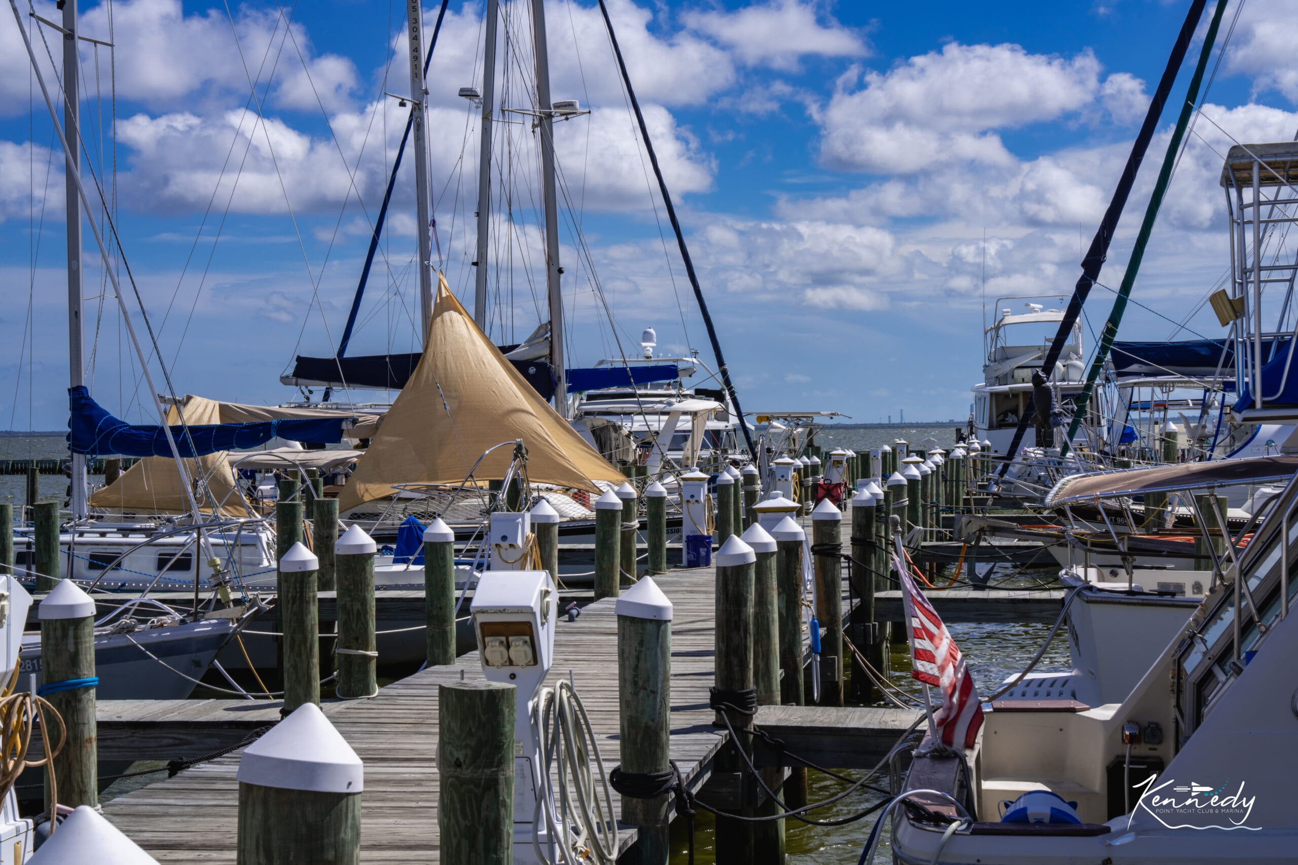 Sailboats and motor yachts moored along wooden docks with power pedestals at Kennedy Point Yacht Club & Marina, Kennedy Point.