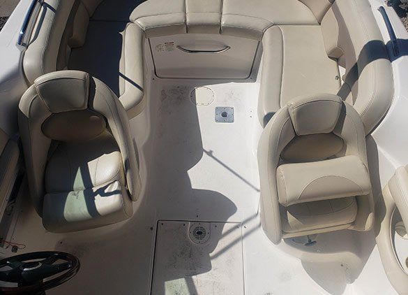 Overhead view of a boat's tan leather helm and passenger seats on a white deck.