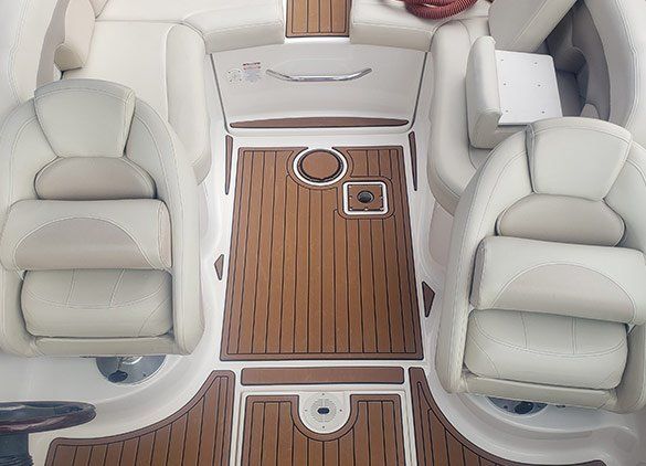 Boat cockpit with white bucket seats and new synthetic teak-style decking, shown as a sample of marine deck replacement work.