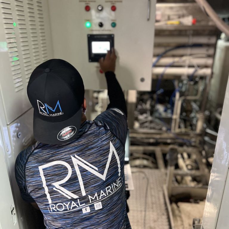 Technician operating a touchscreen control panel in a vessel machinery space at Royal Marine, town unknown.