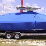 A blue canvas cover fitted over a center console boat resting on a twin-axle trailer.
