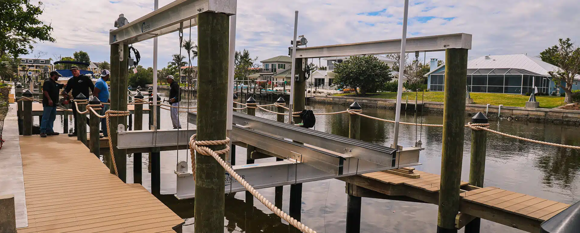 Aluminum boat lift under installation on a residential canal dock with workers present, Crocker Marine Services, Fort Myers.
