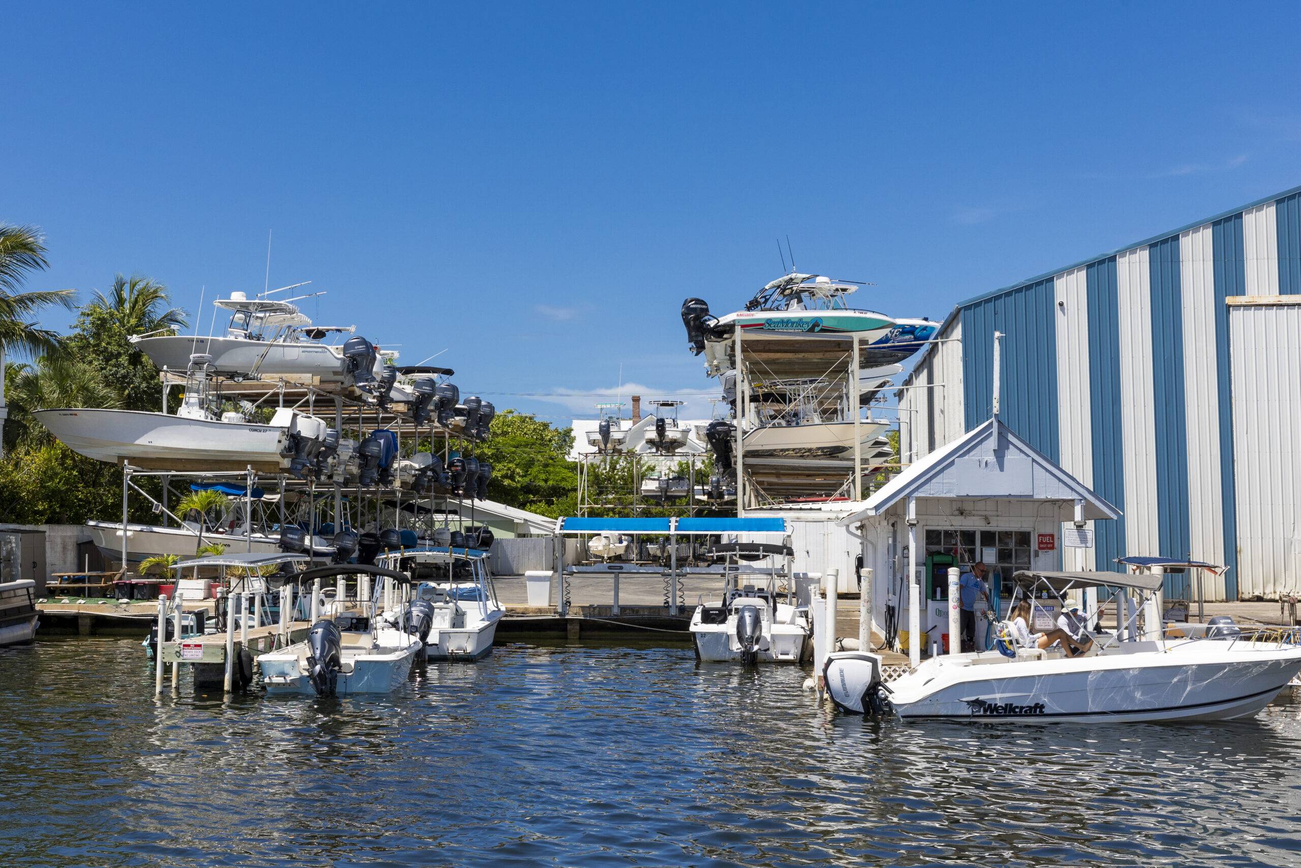 Dry-stack boat storage racks, fuel dock, and moored powerboats at a waterfront marina.