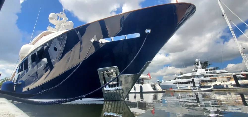 Dark-blue motor yacht moored at a dock in a Fort Lauderdale-area marina, with other superyachts nearby.