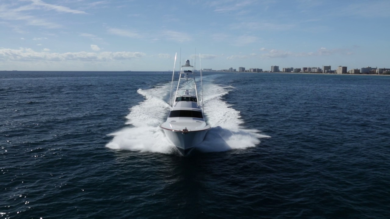 Sportfishing yacht underway with a white wake off a coastal city skyline, Fort Lauderdale area