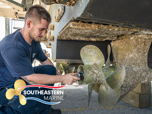 Technician inspecting a barnacle-fouled propeller on a boat hauled out at Southeastern Marine.