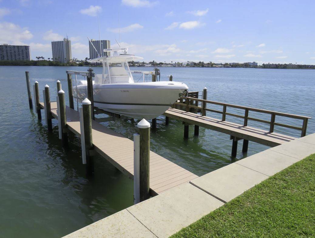 White center-console boat raised on a lift at a waterfront dock with high-rise buildings in the background.