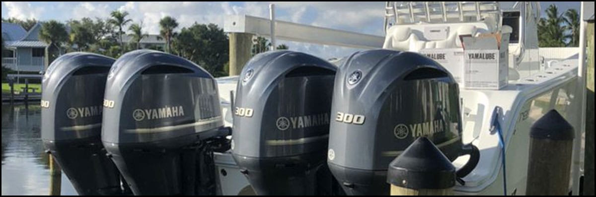 Four Yamaha 300 outboard motors mounted on the back of a white center-console boat at a dock.