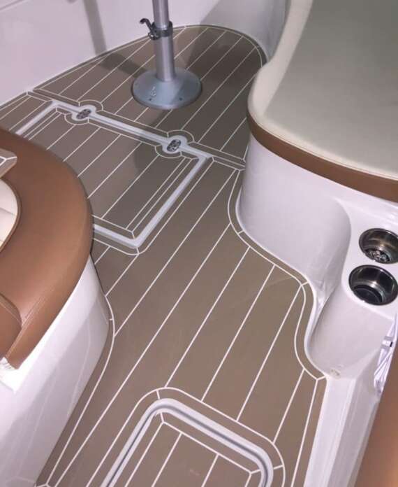 Synthetic teak deck flooring with white seams and a pedestal table base inside a boat cockpit.