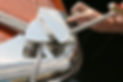Close-up of a person's hands and white shoes on a boat deck or dock edge.