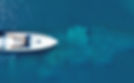 Aerial view of a white boat on blue water.